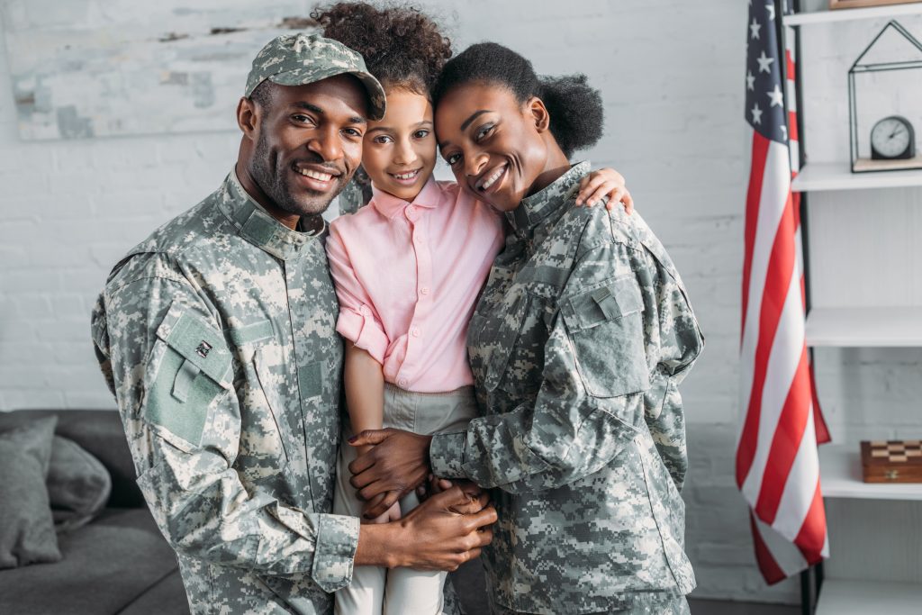 A smiling military family with an American flag in the background