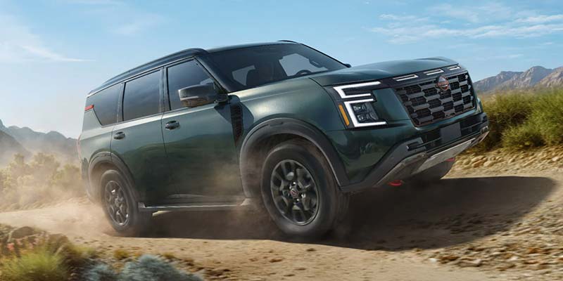 2026 Nissan Armada full-size SUV driving on a rugged dirt road, highlighting its strong build and advanced safety-focused design.