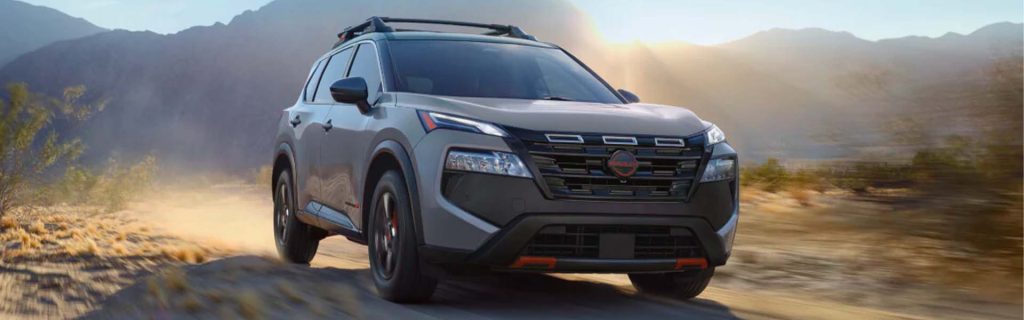 Gray 2026 Nissan Rogue SUV driving off-road through a dusty desert landscape, highlighting its adventurous capability and innovative design.