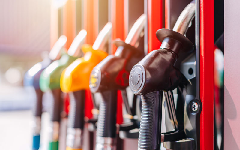 Close-up row of colorful fuel pump nozzles at a gas station, representing fuel savings and efficiency tips for Nissan vehicles.