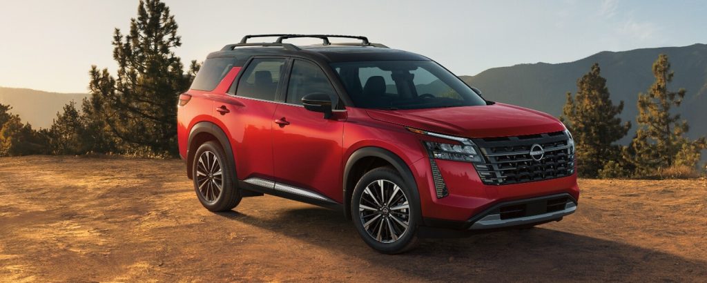 Red Nissan Pathfinder SUV parked on a mountain overlook road.