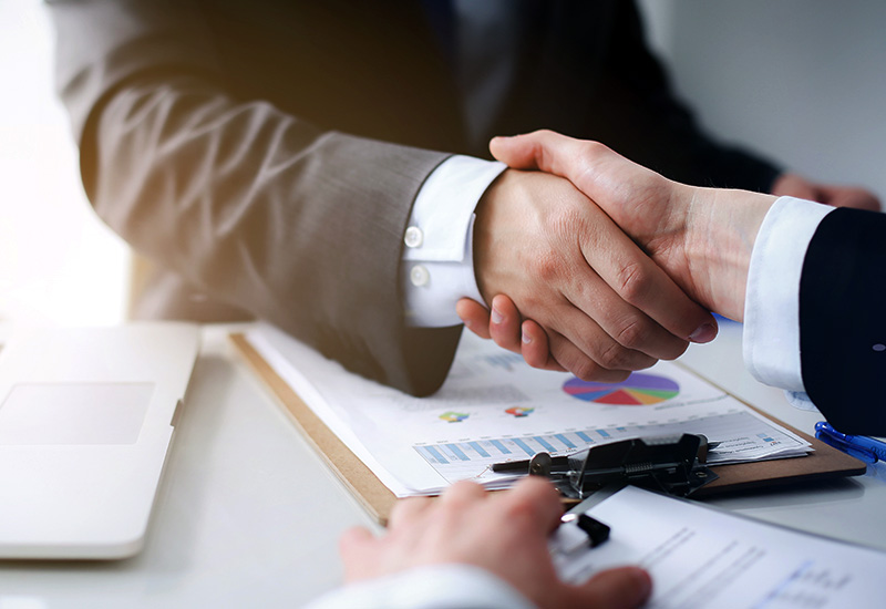 Business handshake over documents and laptop